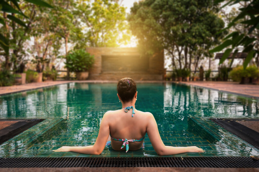 Jeune femme de dos dans une piscine bordée de végétation