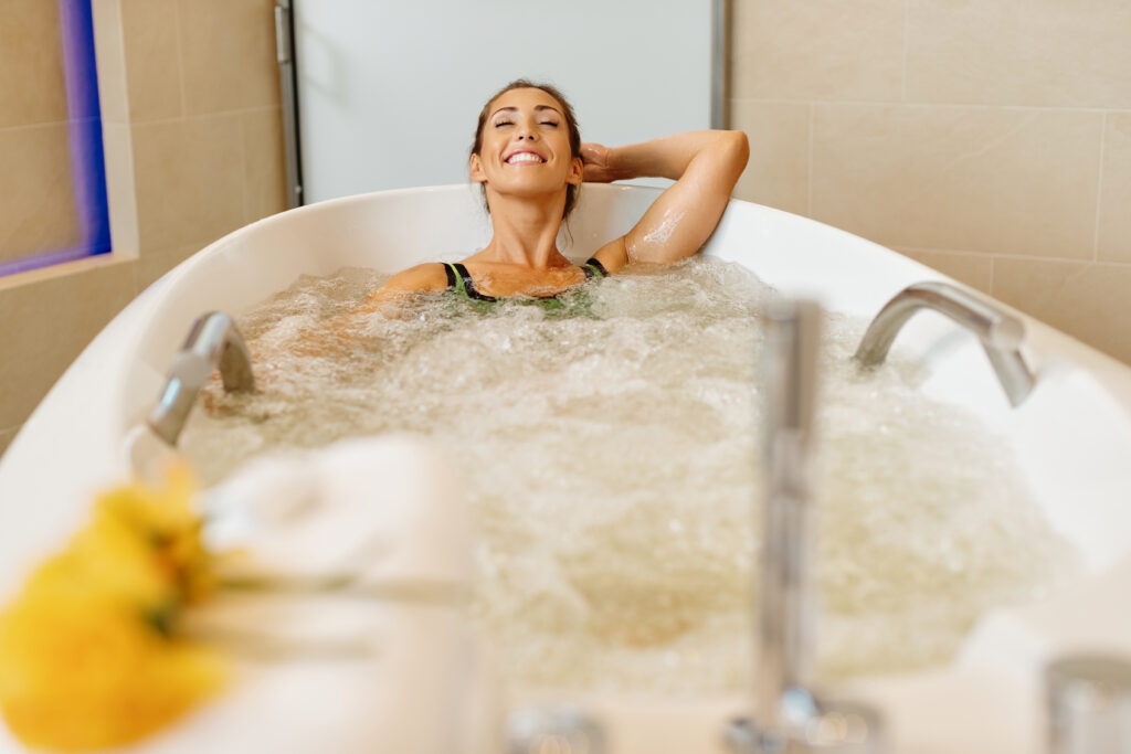 Jeune femme souriant dans un bain bouillonnant