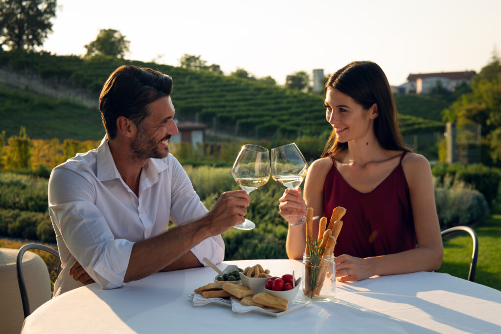 Un homme et une femme qui trinquent devant un paysage de vignes