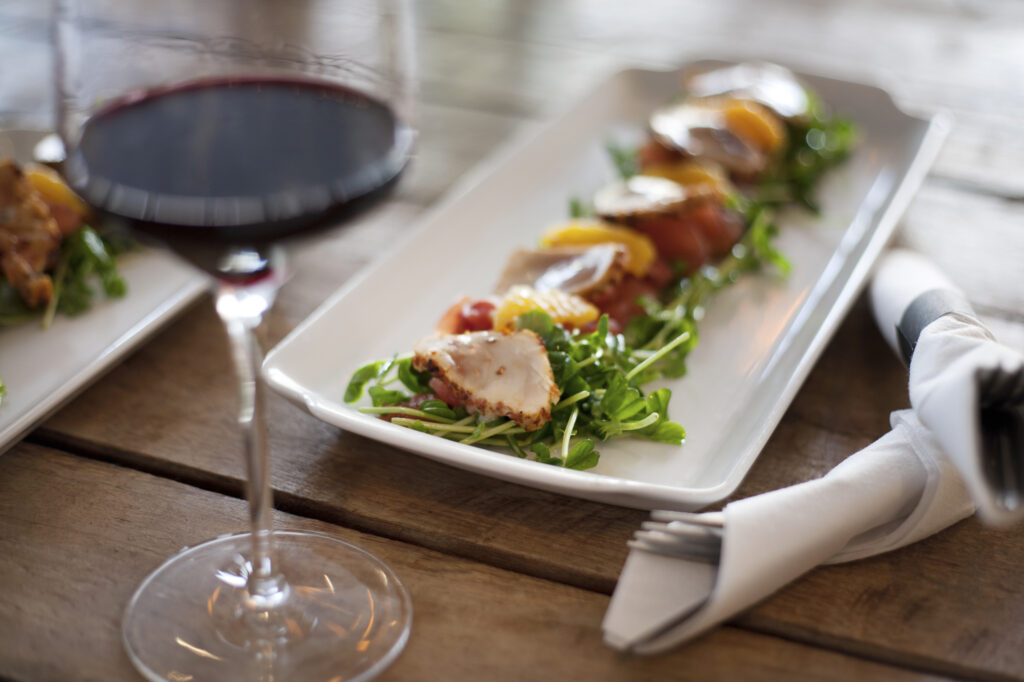 Verre de vin rouge devant une assiette d’amuse-bouches