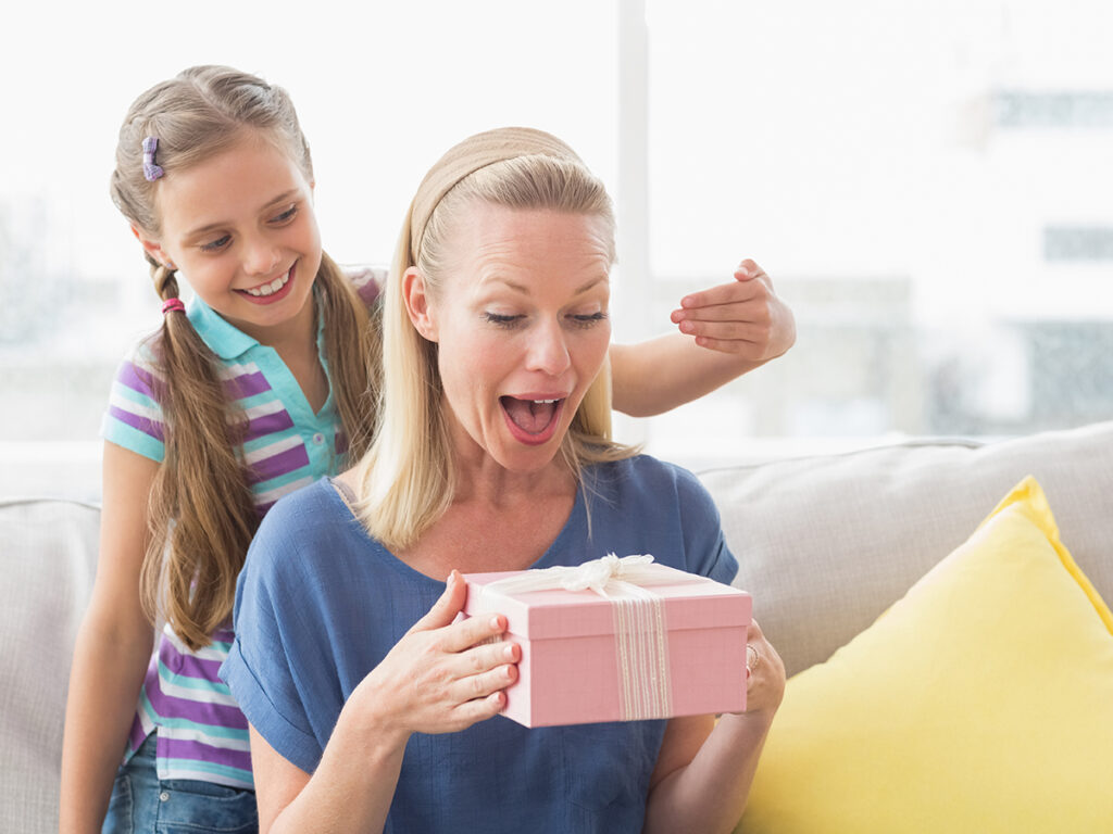 Jeune fille surprenant sa mère avec un cadeau à la maison