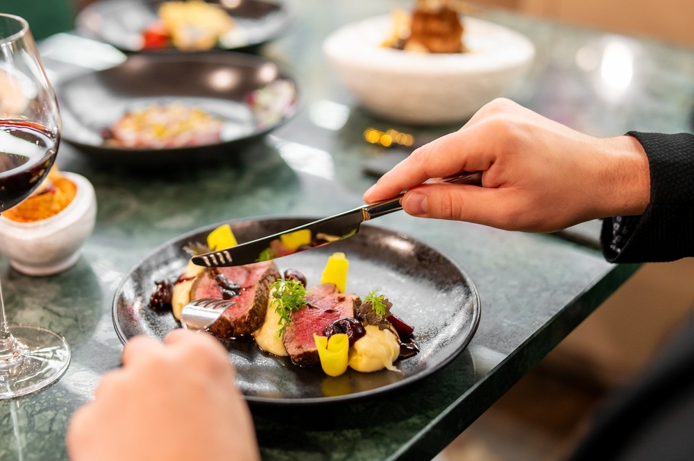 Un homme mange de la viande avec du vin rouge dans un restaurant gastronomique