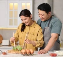 Couple heureux et charmant cuisinant ensemble dans la cuisine. C'est une activité qu'ils réalisent à l'occasion de la saint-valentin.