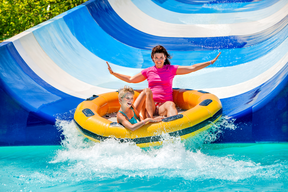Enfant avec sa mère sur le toboggan aquatique d'un parc aquatique. Deux personnes en vacances d'été.