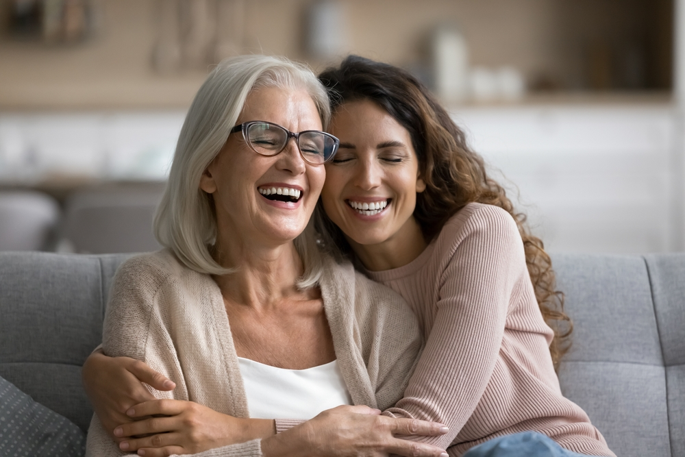 Une mère âgée et sa fille adulte s'amusent à la maison, sont assises sur le canapé, s'amusent et passe un bone momment à l'occasion de la fête des mères.