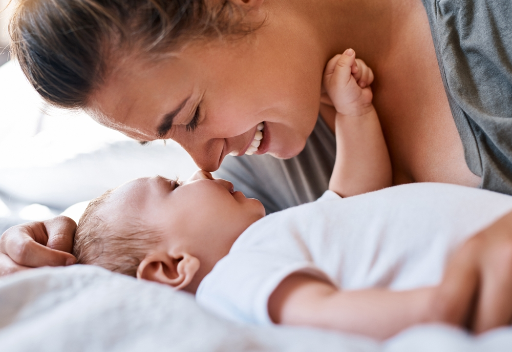Maman, bébé et heureux sur le lit dans la chambre en jouant pour créer des liens, des souvenirs d'enfance et un sourire avec le tout-petit.