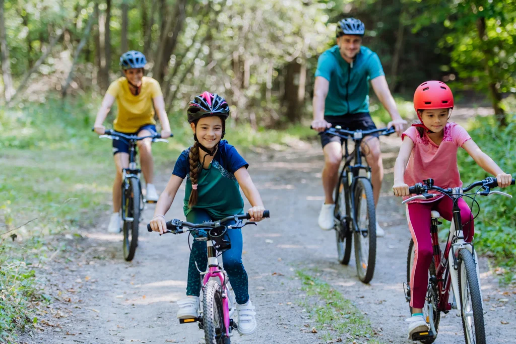 Jeune famille avec de jeunes enfants en balade à vélo dans la nature à l'occasion de la fête des pères.