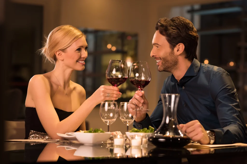 Couple trinquant avec des verres de vin à l'occasion de la fêtre des pères lors d'un dîner romantique dans un restaurant gastronomique.