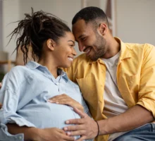 Couple aimant serrer dans ses bras le futur bébé, mari touchant le ventre de sa femme enceinte, assis sur le canapé à la maison.