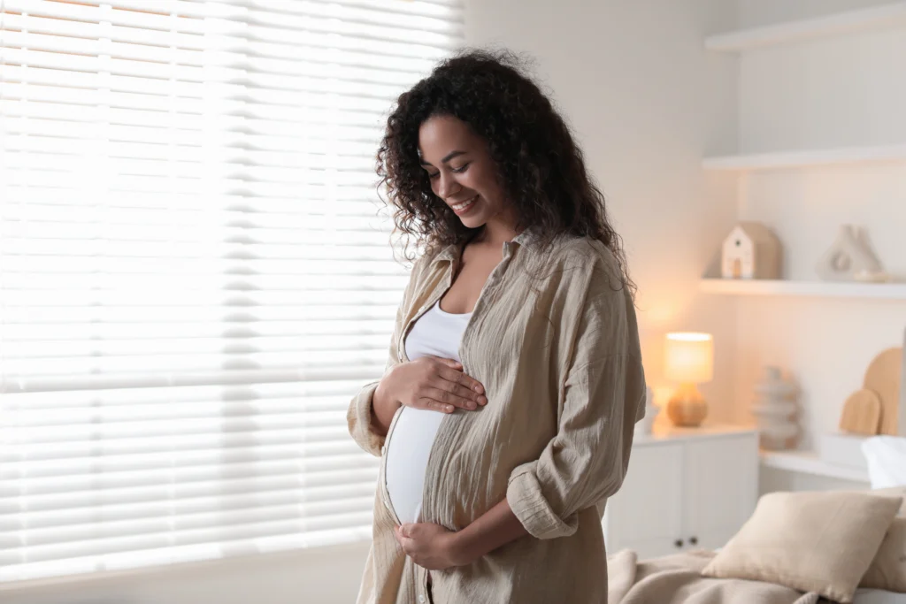 Portrait d'une belle femme enceinte près d'une fenêtre à la maison.