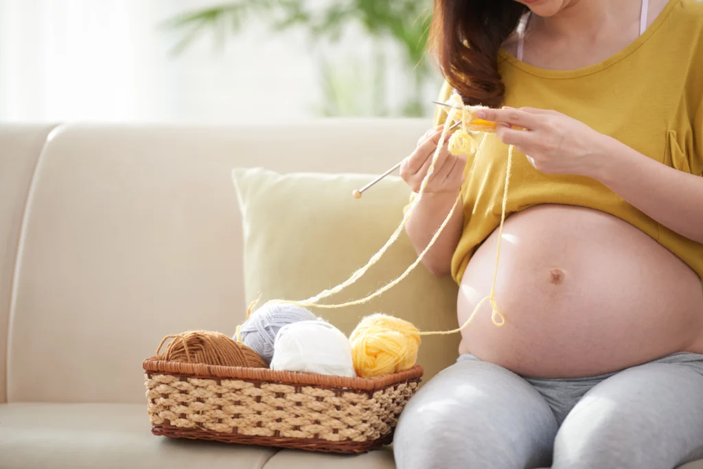 Image recadrée d'une femme enceinte tricotant.