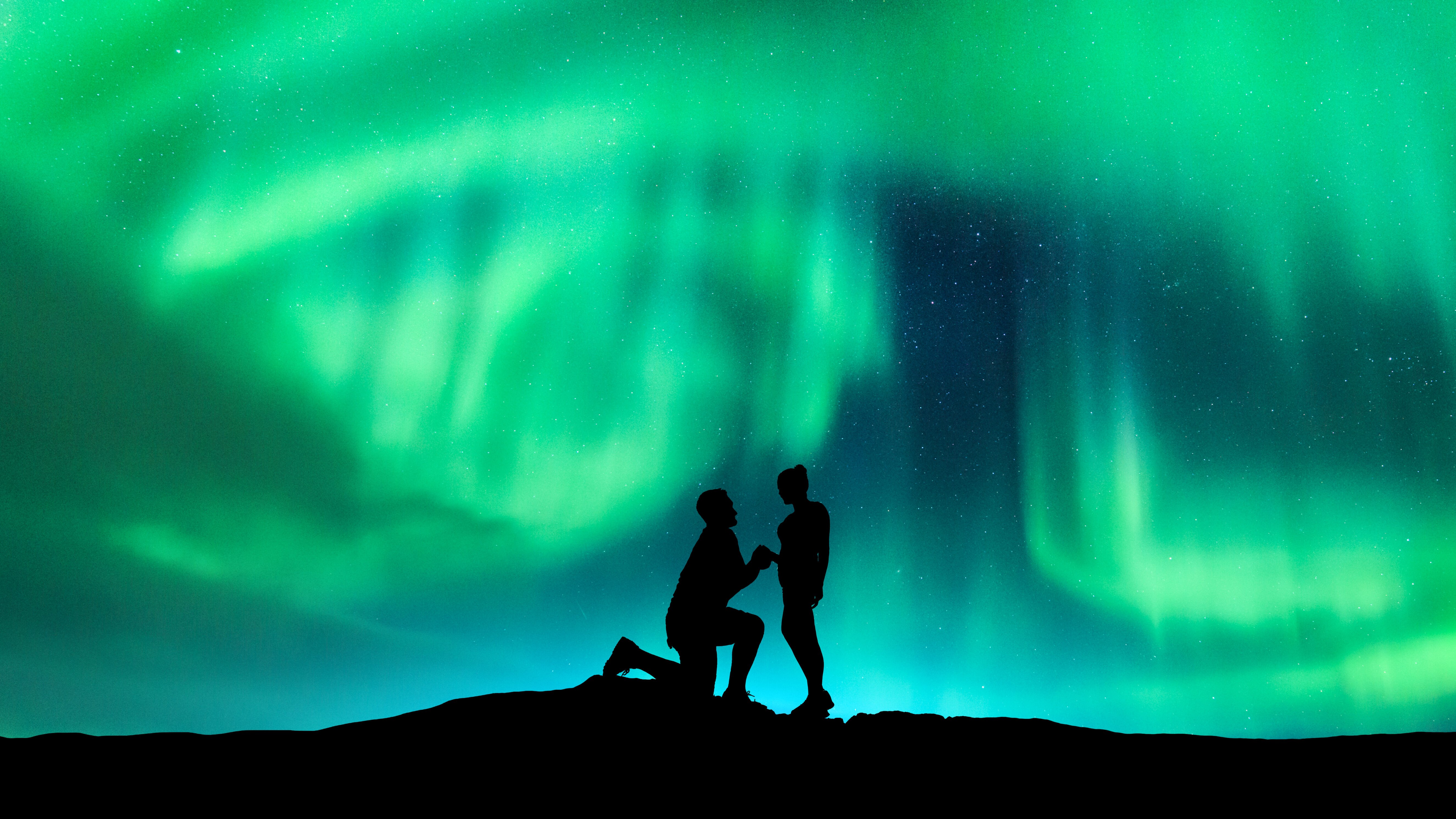 Aurore boréale et silhouette d'un homme faisant une demande en mariage à sa petite amie. Paysage nocturne avec aurores boréales, ciel étoilé et amoureux.