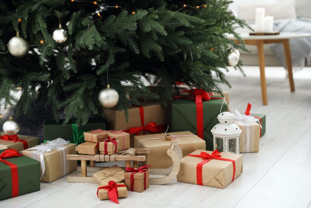 Coffrets de cadeaux noel tendances joliment emballés, traîneau en bois et lanterne sous le sapin de Noël à l'intérieur.