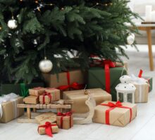 Coffrets de cadeaux noel tendances joliment emballés, traîneau en bois et lanterne sous le sapin de Noël à l'intérieur.