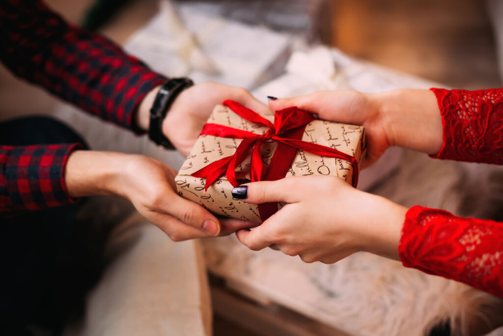 Un homme offre un cadeau de noel à une femme qu'il connaît peu.