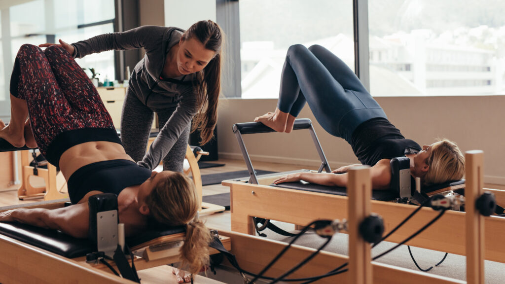 Instructora de pilates enseñando a alumnas en máquinas de pilates