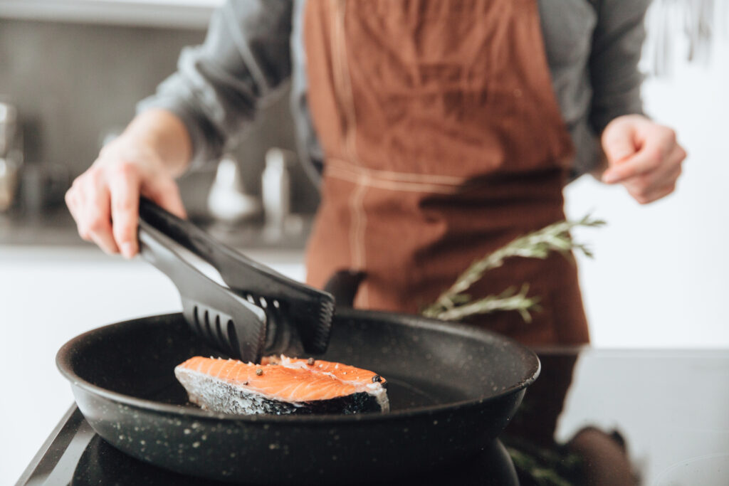 Chica cocinando salmón a la plancha