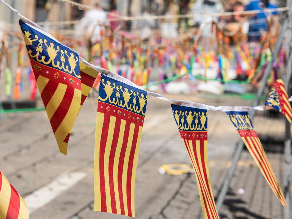 Tira de banderas de Valencia rondeando una mascletá