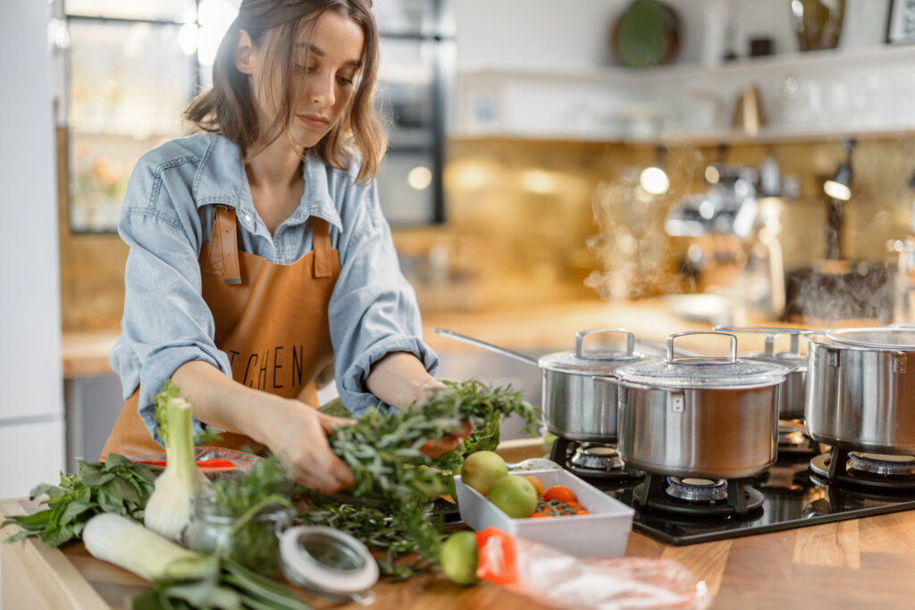 Una chica cocinando un plato de verduras