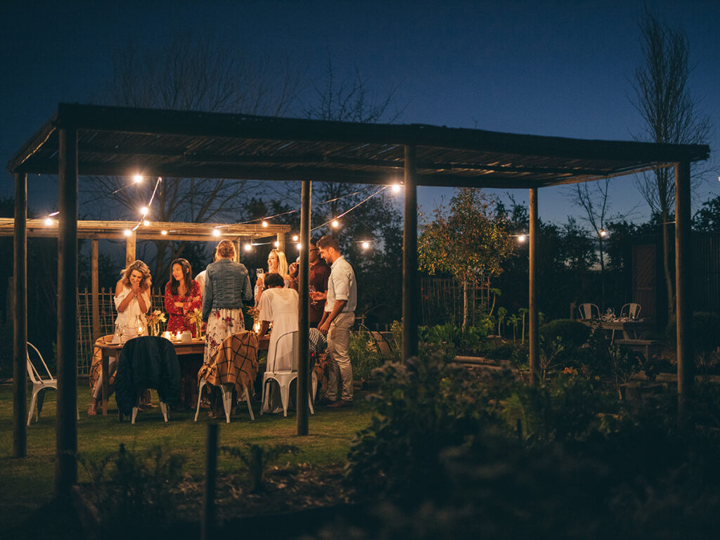 Grupo de amigos alrededor de una mesa durante la cena en un jardín