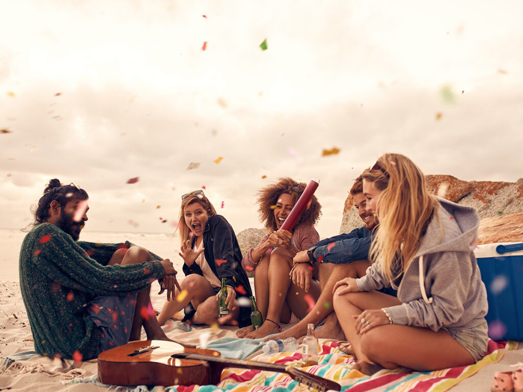 Grupo de amigos reunidos en la arena de la playa celebrando