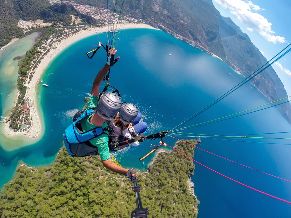 Dos personas realizando parapente sobre la costa