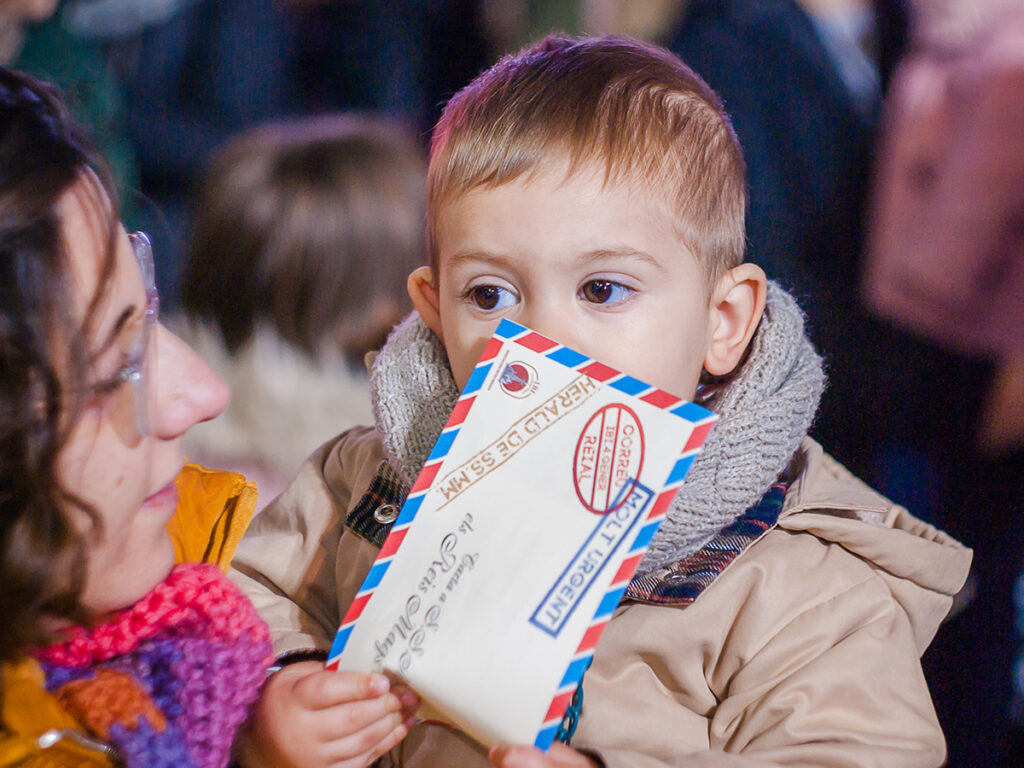 Un niño en la cabalgata de los Reyes Magos sujetando una carta