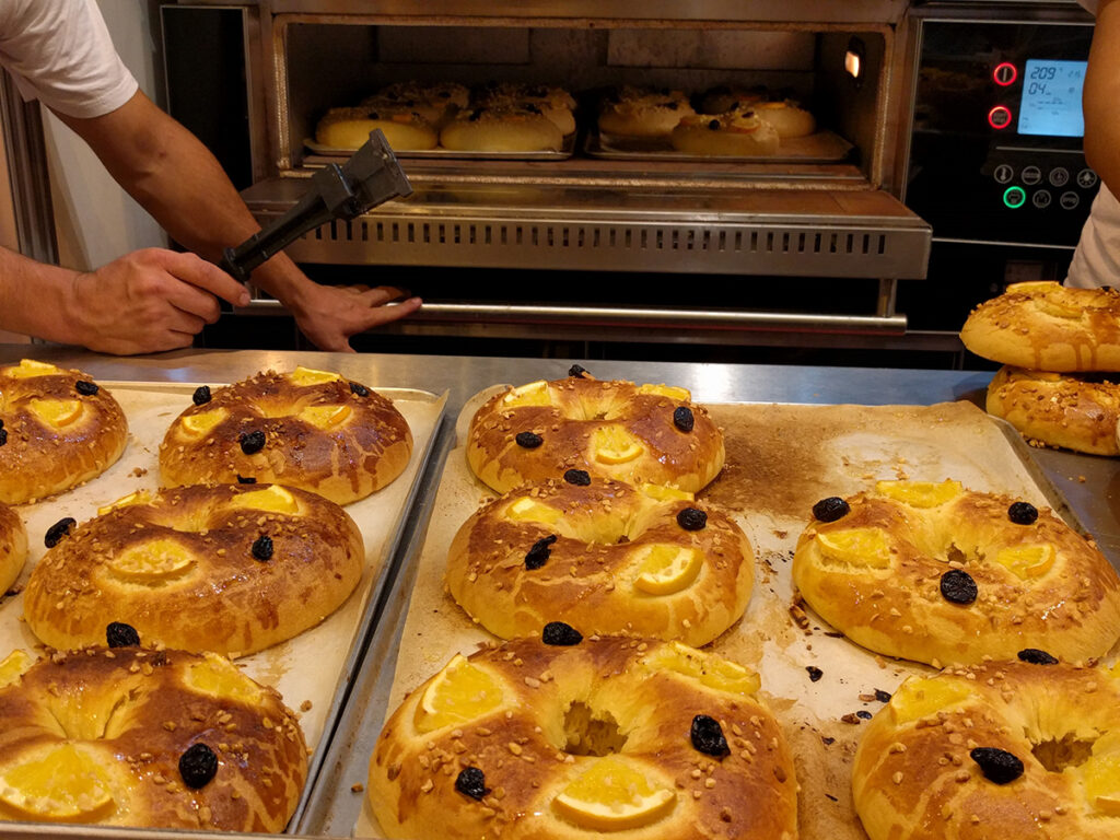 Persona preparando en un horno grande muchos roscones de reyes