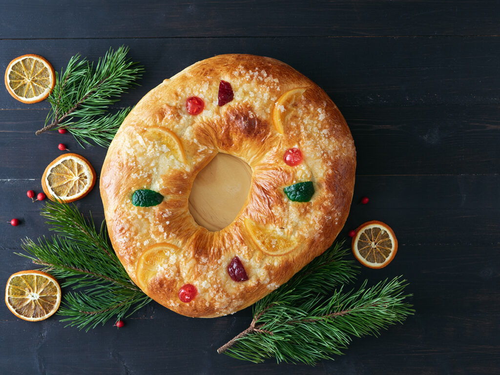 Roscón de reyes en una mesa de color oscuro con decoración alrededor