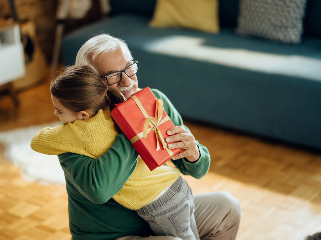 Señor y niña pequeña abrazándose con un regalo