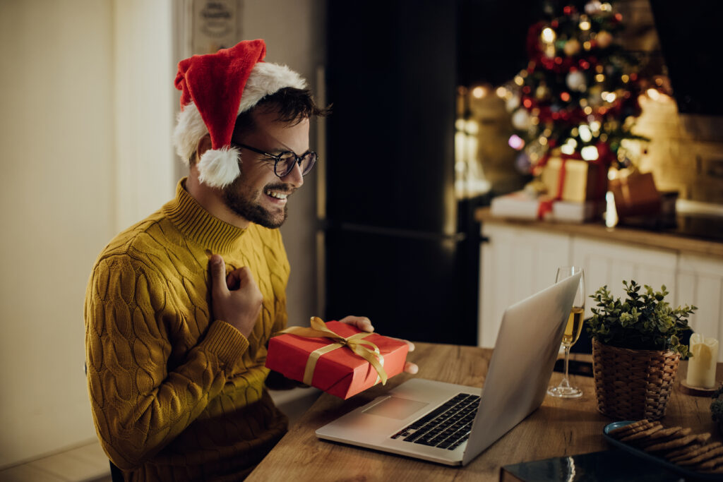 Homme échangeant virtuellement des cadeaux de Noël lors d'un appel vidéo sur un ordinateur