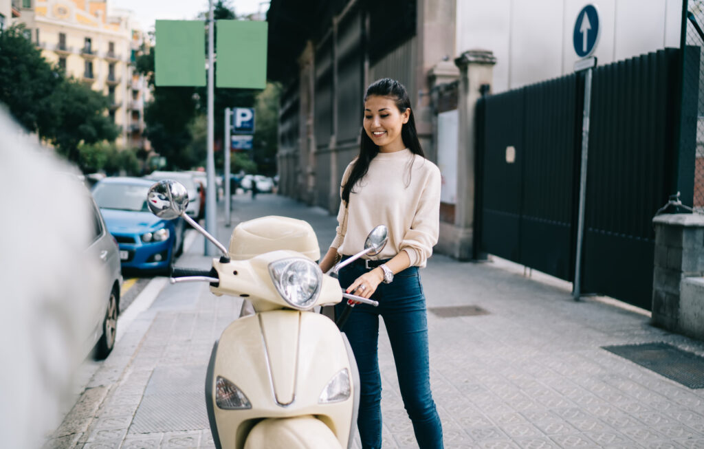 Femme à côté d'une vespa dans la rue