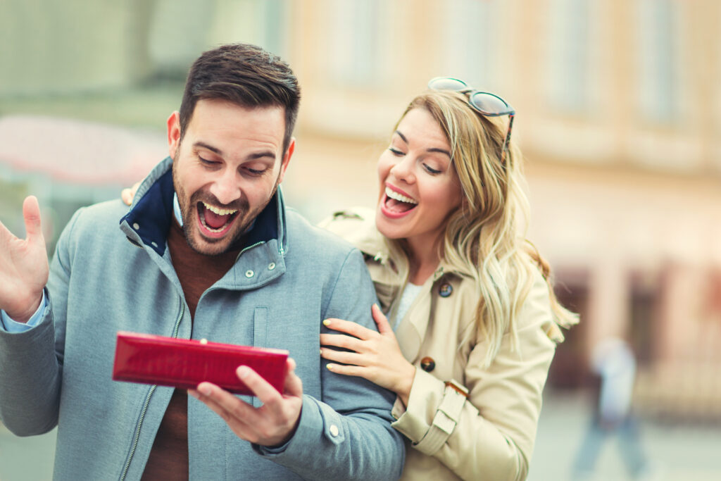 Femme qui surprend son mari dans la rue avec un cadeau