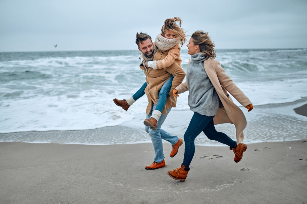 Un couple et leur fille sur une plage en hiver