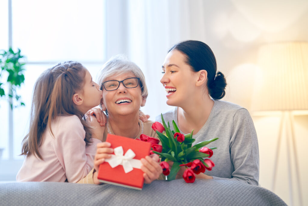 Une grand-mère recevant un cadeau entre sa fille et sa petite-fille