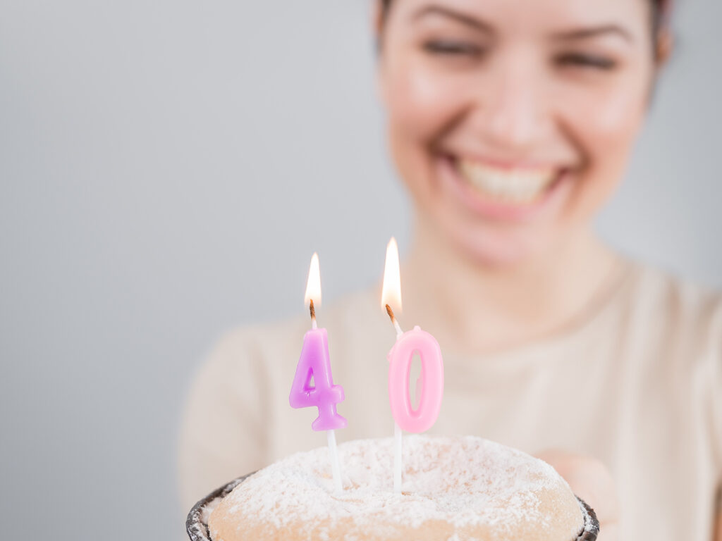 Femme souriant devant un gâteau d’anniversaire pour ses 40 ans
