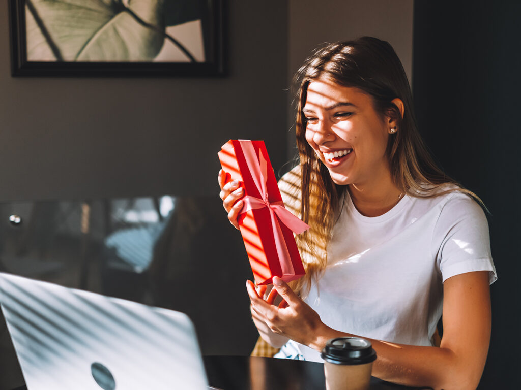 Femme ouvrant un cadeau devant son ordi