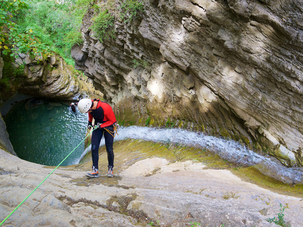 Homme pendant une séance de canyoning qui descend en rappel