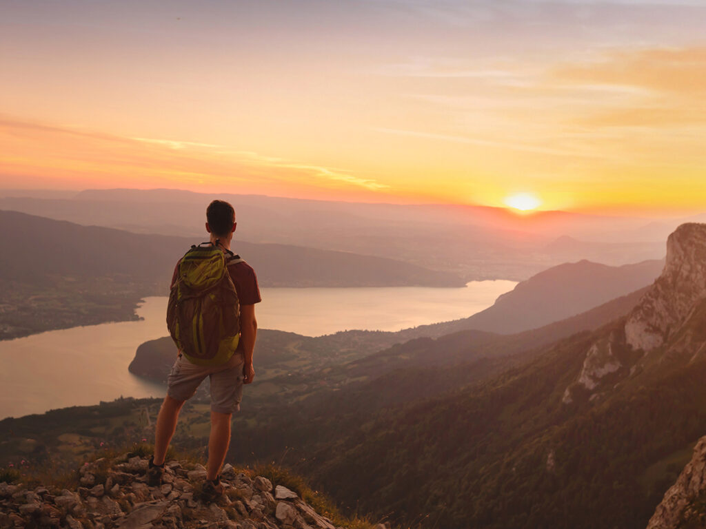 Un randonneur face au lac d’Annecy au coucher du soleil