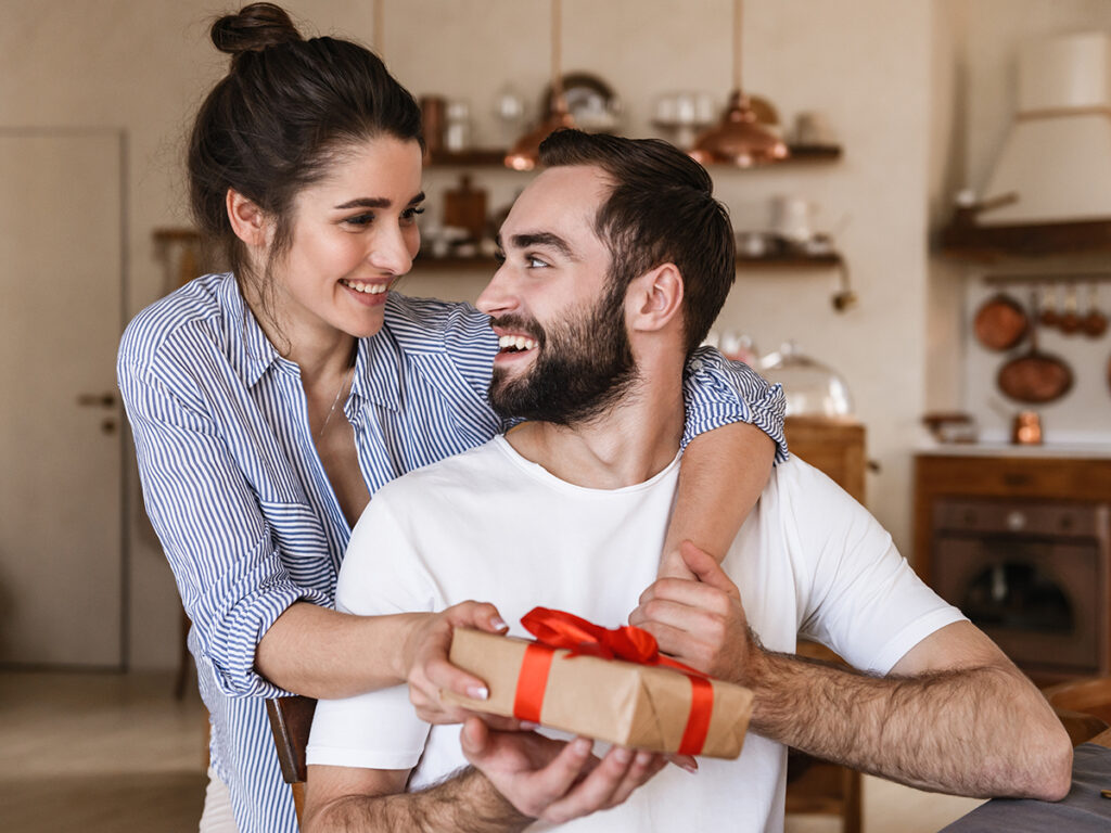 Une jolie jeune femme offrant un cadeau à un jeune homme