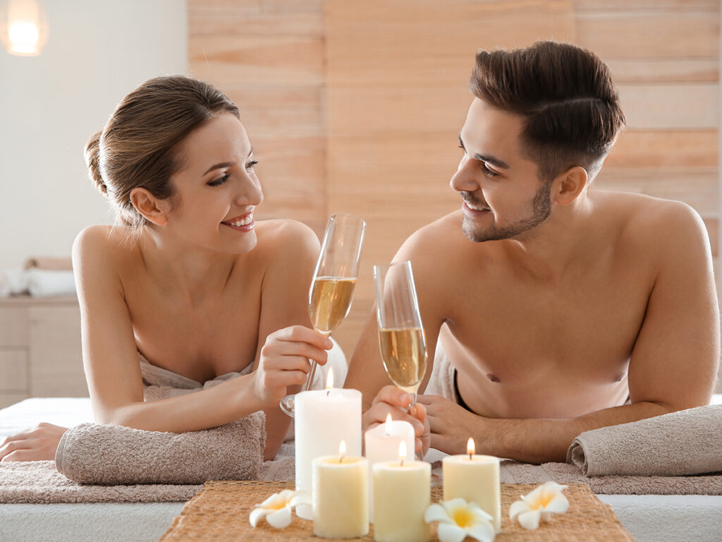 Couple allongé dans un centre de bien-être qui trinque au champagne