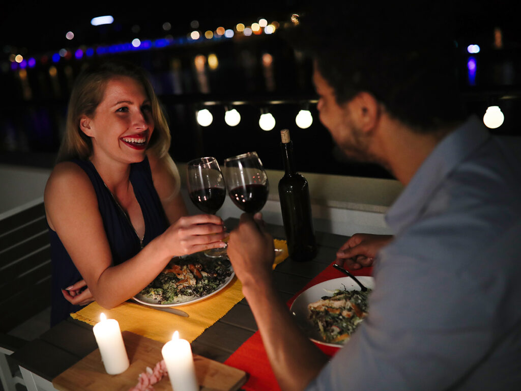 Couple qui se sourit et qui trinque à table au restaurant