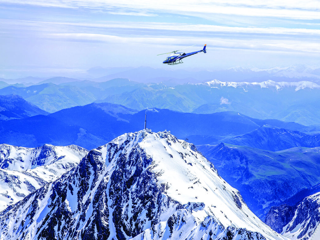 Hélicoptère survolant un pic enneigé