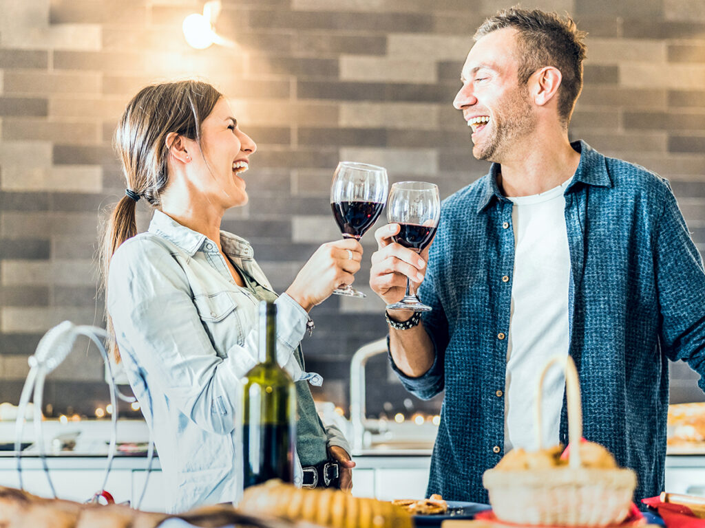 Coppia felice che brinda a casa con un calice di vino