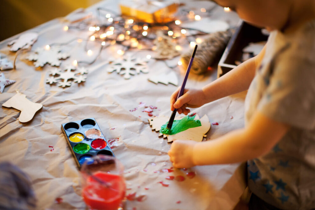 Un bambino decora un albero di Natale fatto a mano