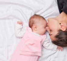 Una neo mamma sul letto insieme al suo bambino