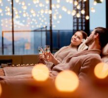 Una coppia distesa sui lettini mentre brinda alle terme per San Valentino