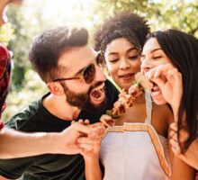 Amici provano ad addentare carne in una grigliata